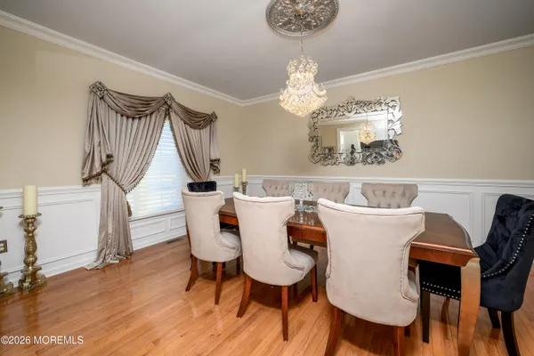a dining room with wooden floor a chandelier a wooden table and chairs