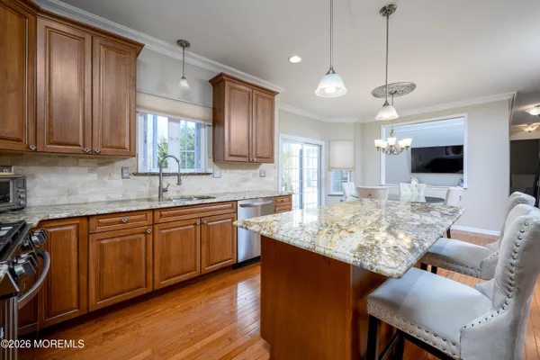 a kitchen with kitchen island granite countertop a stove top oven a sink dishwasher a dining table and chairs with wooden floor