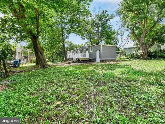 a view of a house with a big yard and large trees