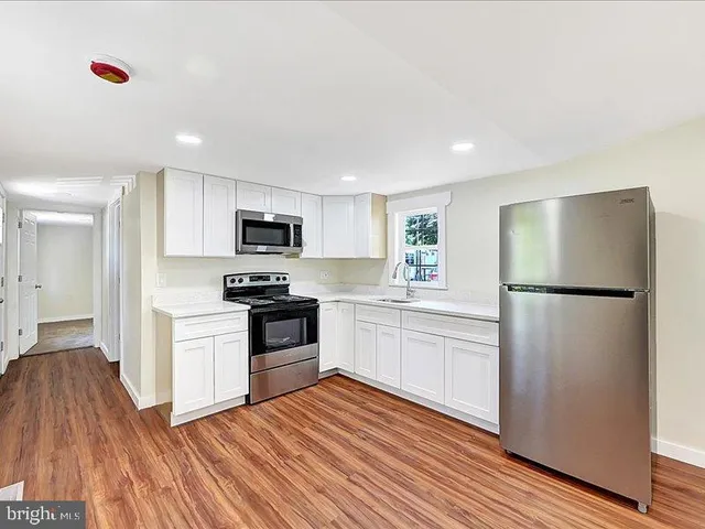 a kitchen with a refrigerator a stove top oven and wooden floor