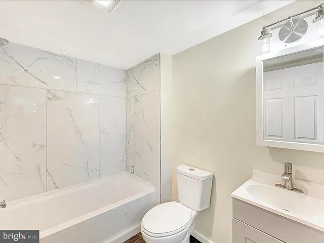 a bathroom with a bathtub shower sink vanity and toilet