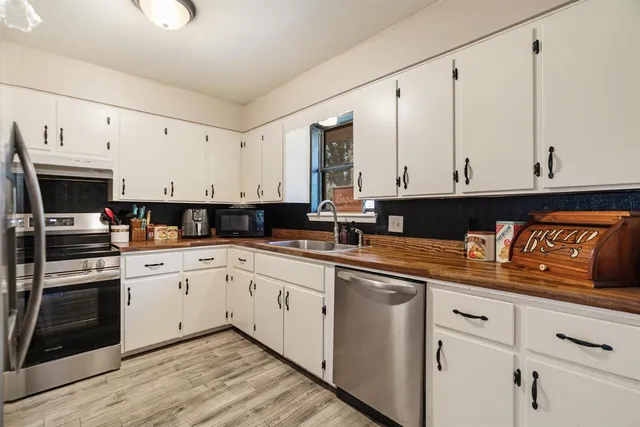 a kitchen with granite countertop white cabinets and stainless steel appliances