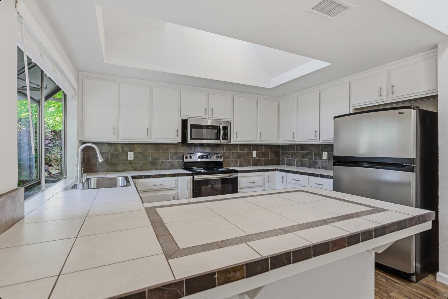 1175 Rose Tree Way Sacramento, CA 95831 - Photo 12 of 33 a kitchen with a refrigerator a stove a microwave and cabinets