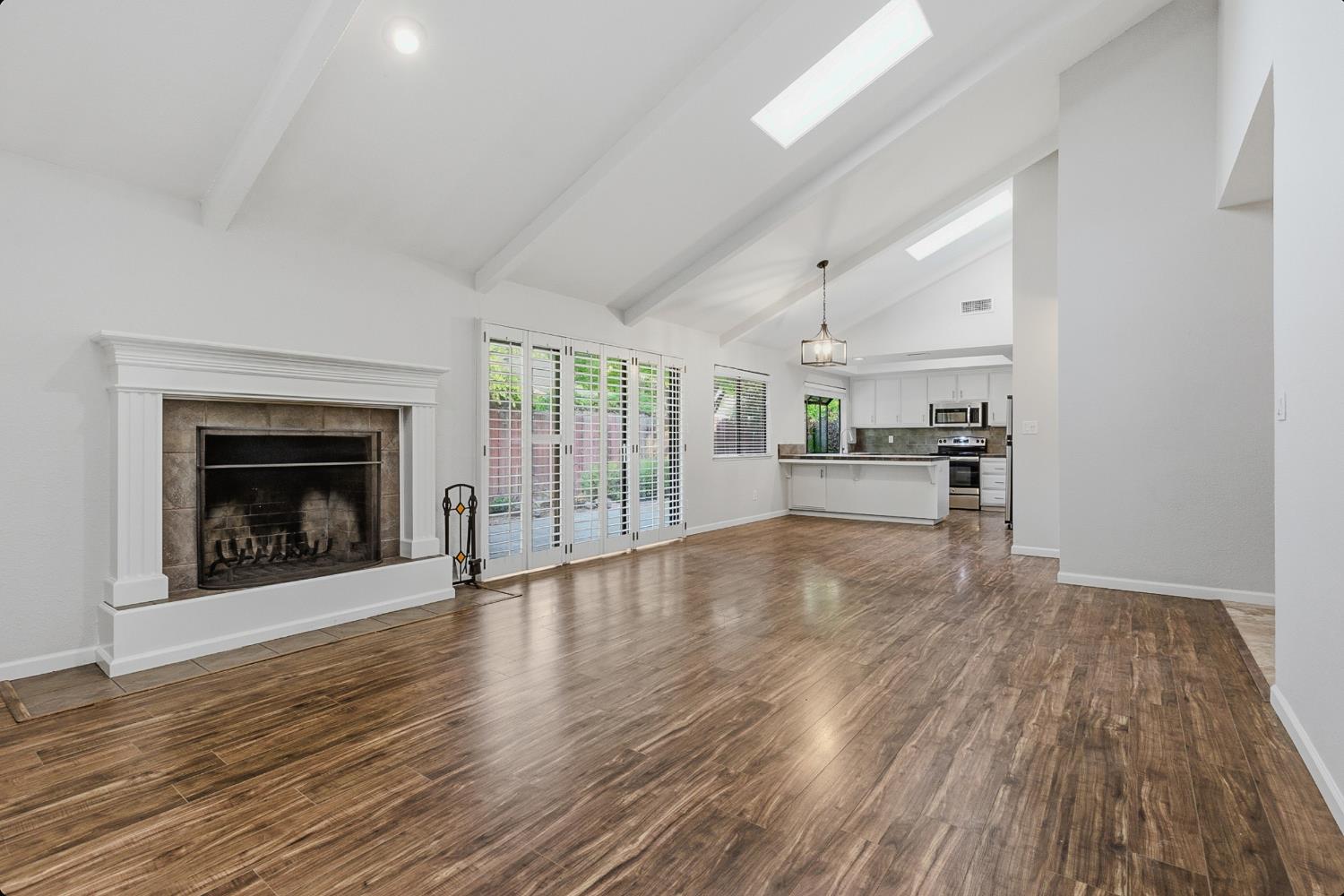 1175 Rose Tree Way Sacramento, CA 95831 - Photo 8 of 33 an empty room with wooden floor a fireplace and windows