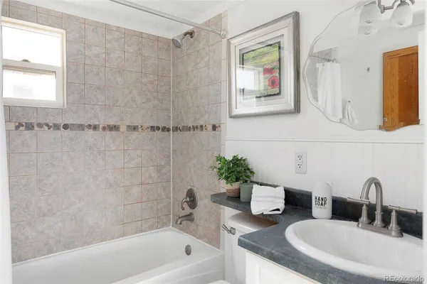 a bathroom with a granite countertop sink a mirror a bathtub and shower