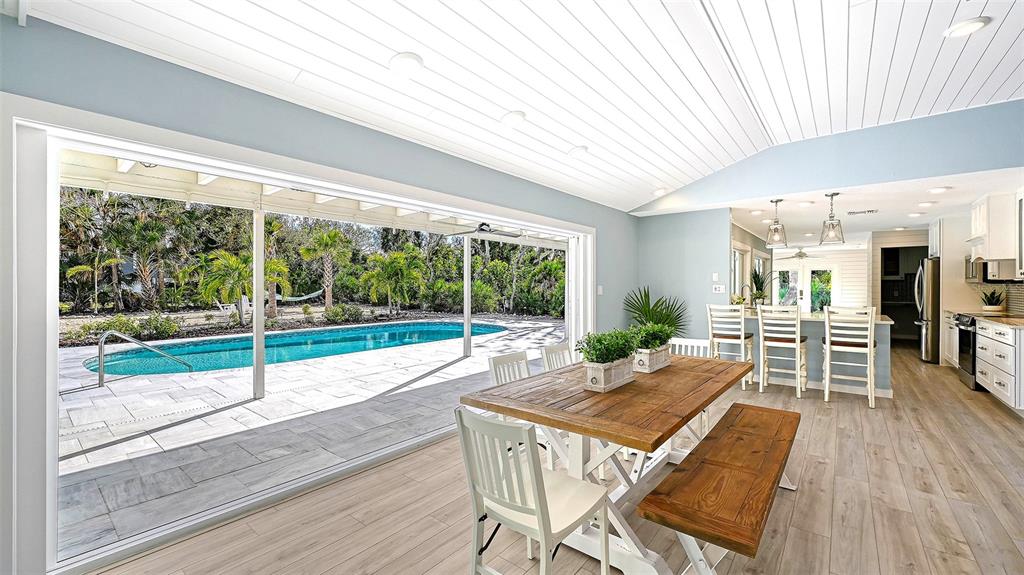 7221 Plovers Way Sarasota, FL 34242 - Photo 15 of 100 a view of a patio with table and chairs floor to ceiling window with wooden floor
