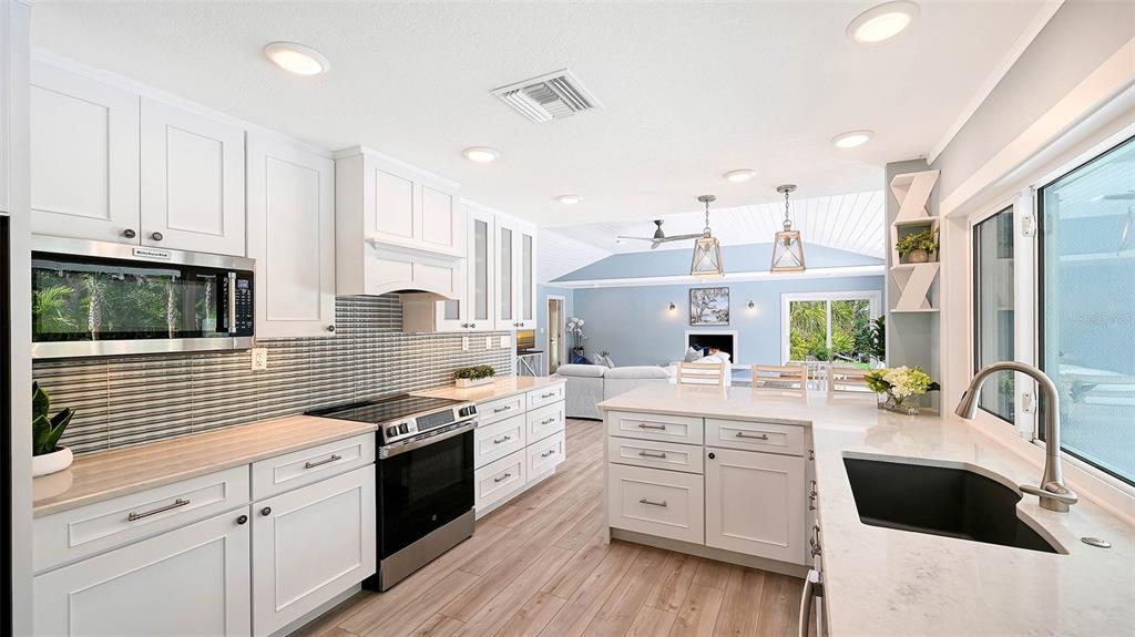 7221 Plovers Way Sarasota, FL 34242 - Photo 18 of 100 a kitchen with stainless steel appliances kitchen island granite countertop a sink stove cabinets and wooden floor