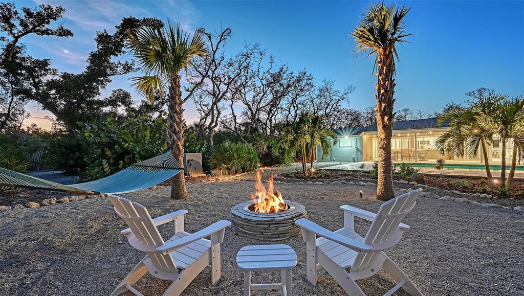 7221 Plovers Way Sarasota, FL 34242 - Photo 71 of 100 a view of a patio with table and chairs potted plants and palm tree