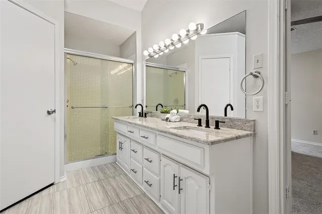 a bathroom with a double vanity sink mirror and shower