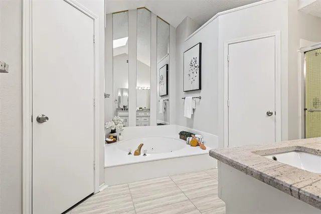 a bathroom with a granite countertop tub sink and mirror