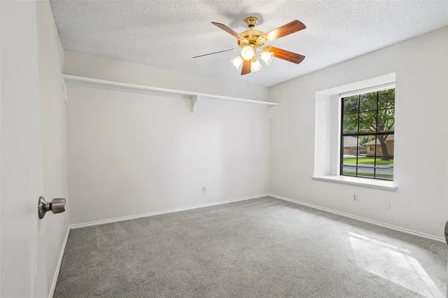 an empty room with a window and a ceiling fan