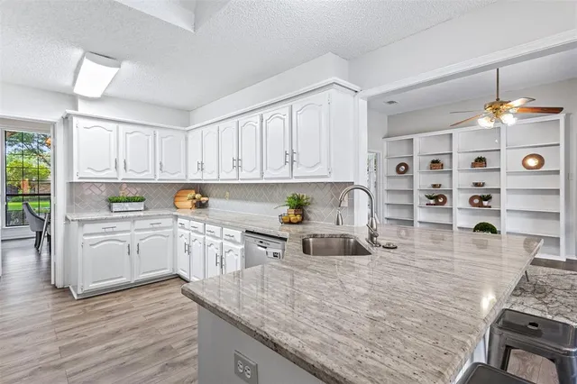 a kitchen with kitchen island granite countertop a sink cabinets and wooden floor