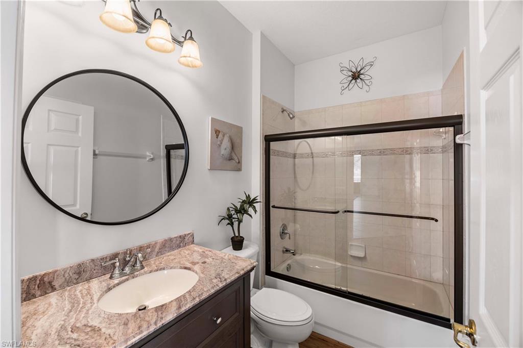 3589 Periwinkle Way Naples, FL 34114 - Photo 19 of 39 a bathroom with a granite countertop sink mirror vanity and toilet