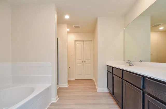 a bathroom with a tub sink and mirror