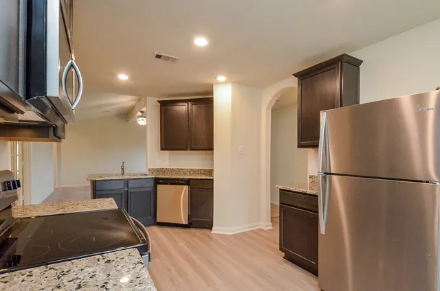 a kitchen with granite countertop a refrigerator and a stove top oven