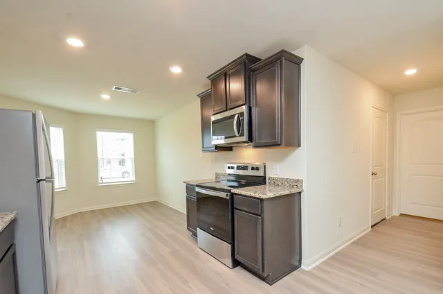 a kitchen with granite countertop wooden cabinets stainless steel appliances and a window