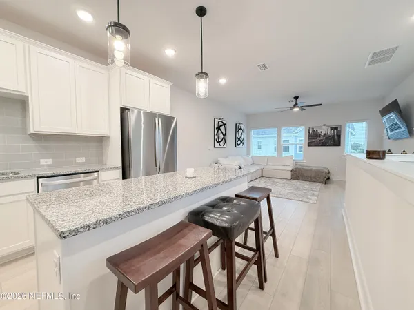 a kitchen with kitchen island granite countertop a table chairs refrigerator and microwave