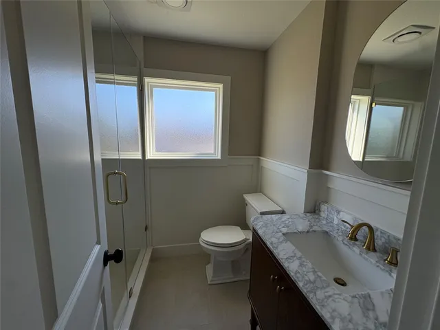 a bathroom with a granite countertop sink toilet and a mirror