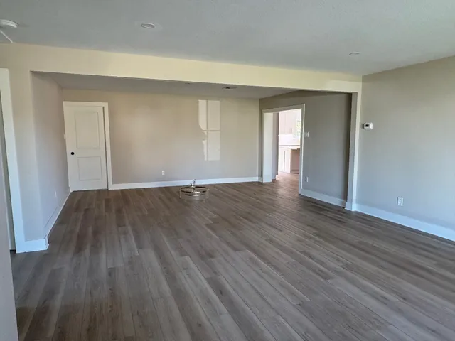 a view of an empty room with wooden floor and a window