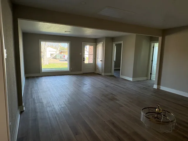 a view of an empty room with window and wooden floor