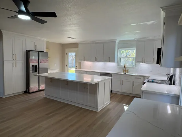a kitchen with kitchen island a counter top space a sink a refrigerator and a stove