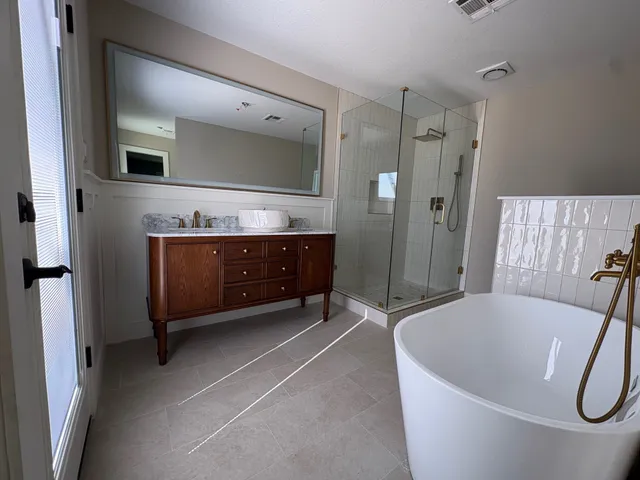 a spacious bathroom with a tub shower and mirror