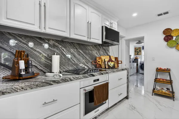 a kitchen with stainless steel appliances granite countertop a sink dishwasher a oven with a dining table and chairs