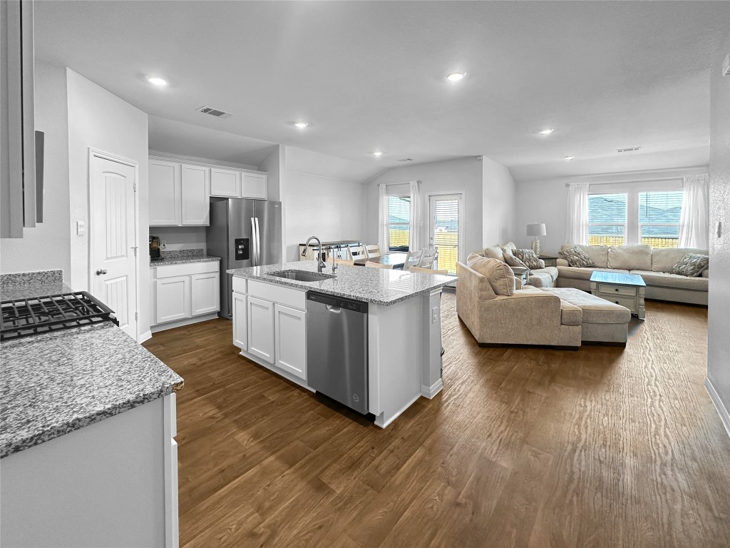 730 Gladiola Loop Kyle, TX 78640 - Photo 3 of 13 Kitchen with light stone countertops, dark wood finished floors, a kitchen island with sink, appliances with stainless steel finishes, and recessed lighting
