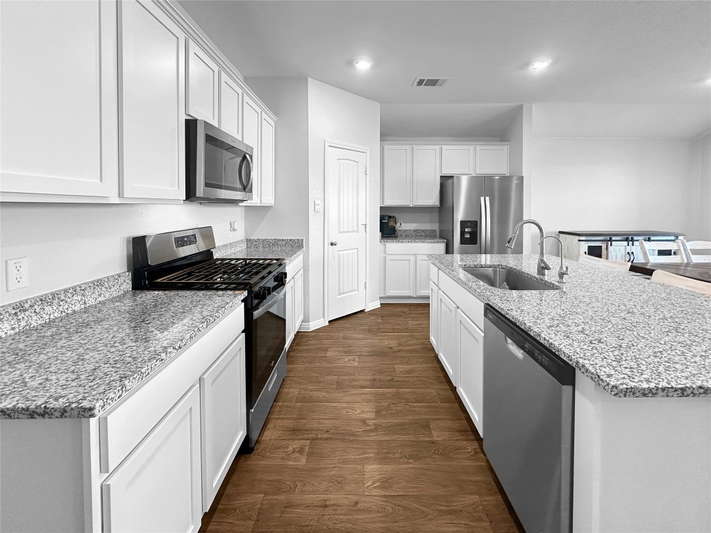 730 Gladiola Loop Kyle, TX 78640 - Photo 5 of 13 Kitchen featuring appliances with stainless steel finishes, dark wood-style floors, white cabinets, light stone countertops, and recessed lighting