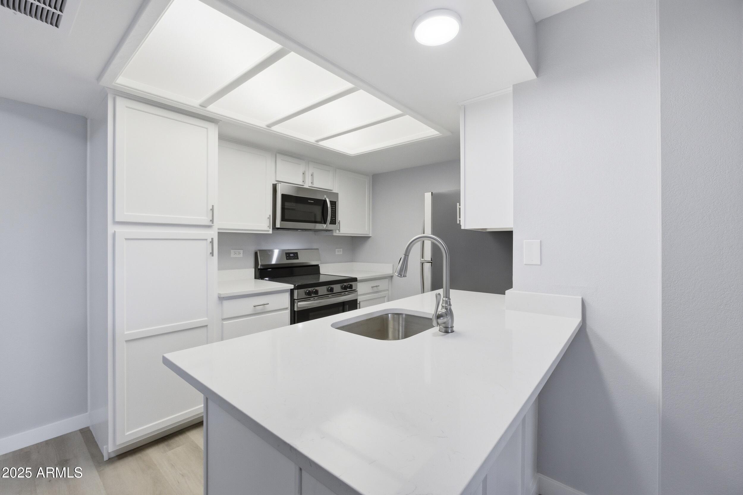 10410 North Cave Creek Road, Unit 2027 Phoenix, AZ 85020 - Photo 7 of 28 a kitchen with stainless steel appliances a sink a stove a microwave a refrigerator a counter top space and cabinets