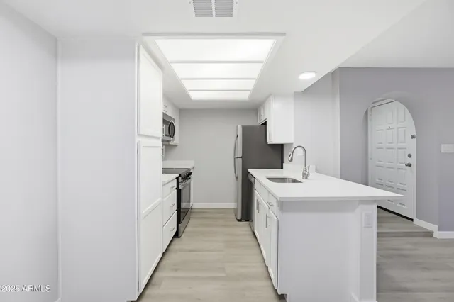 a kitchen with stainless steel appliances a sink a stove a microwave a refrigerator a counter top space and cabinets