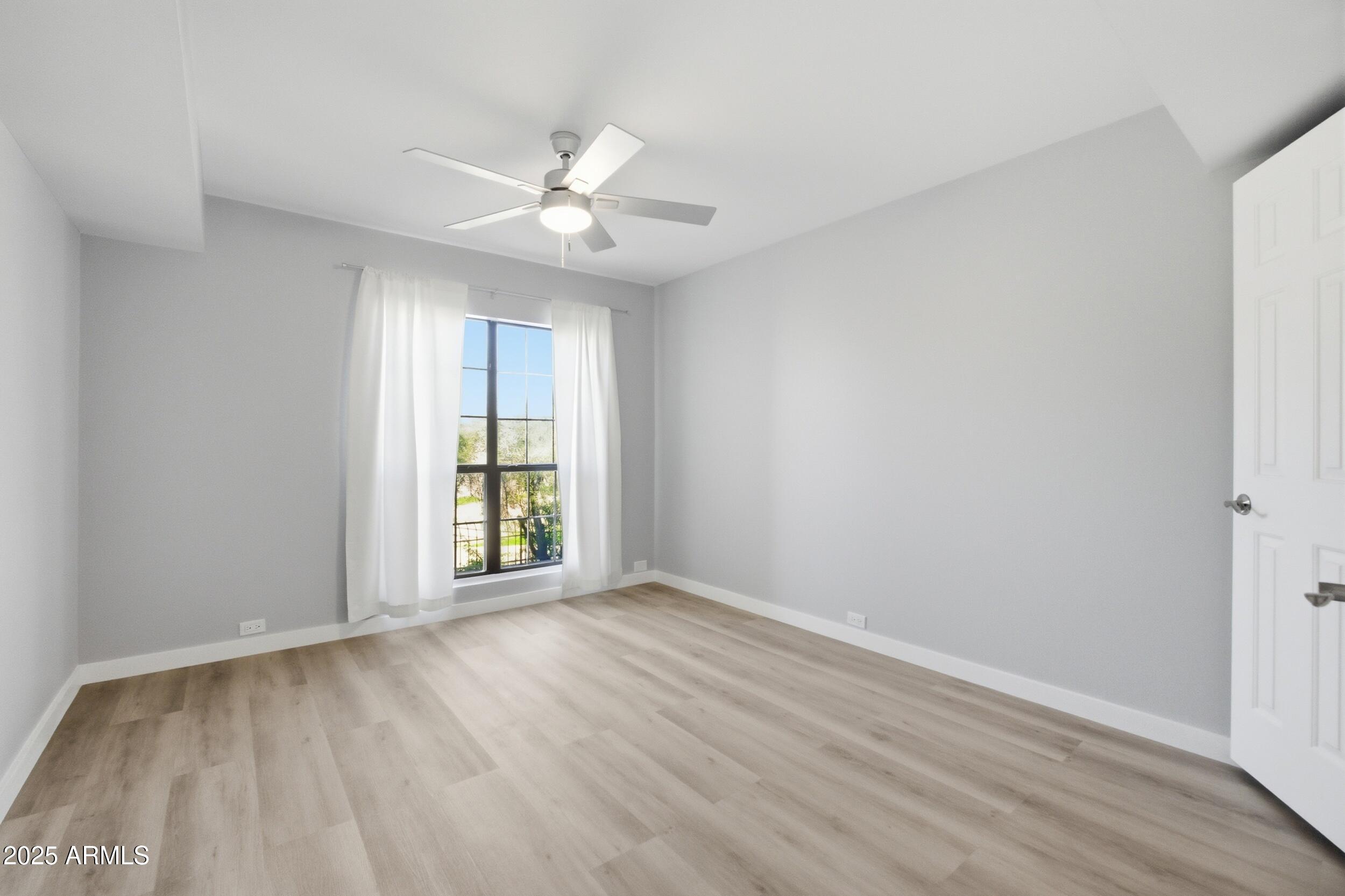 10410 North Cave Creek Road, Unit 2027 Phoenix, AZ 85020 - Photo 9 of 28 an empty room with wooden floor fan and windows