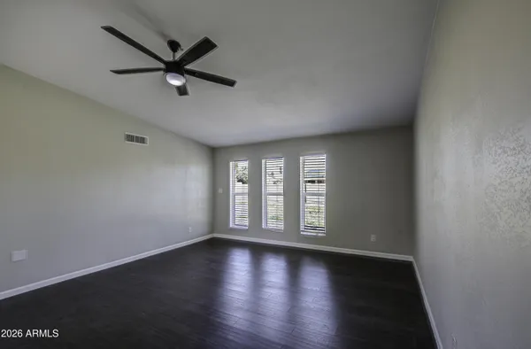 an empty room with wooden floor fan and windows