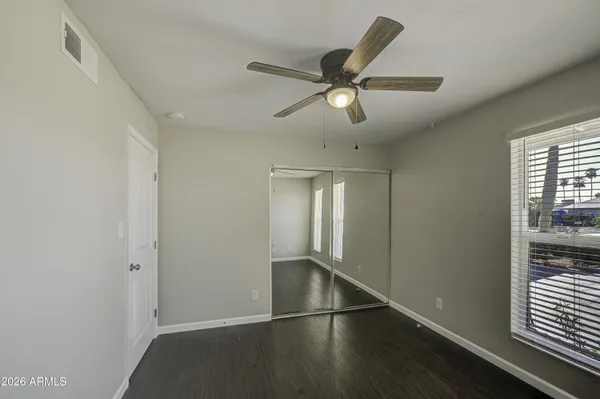 an empty room with wooden floor fan and windows