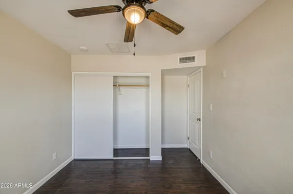 an empty room with wooden floor ceiling fan and window