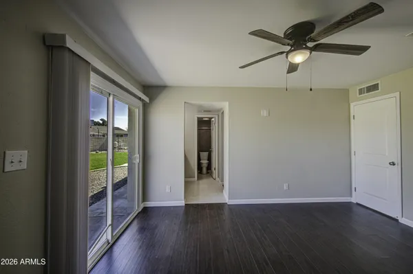 an empty room with wooden floor fan and windows
