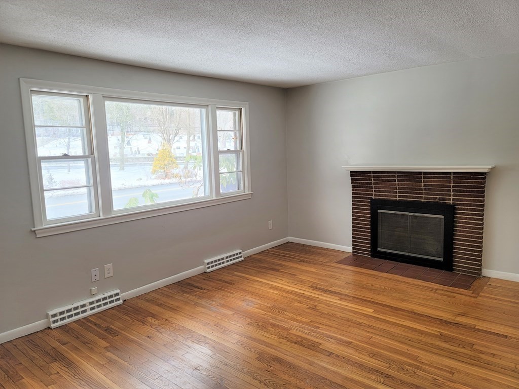 4 Allen Road Billerica, MA 01821 - Photo 4 of 24 an empty room with wooden floor fireplace and windows