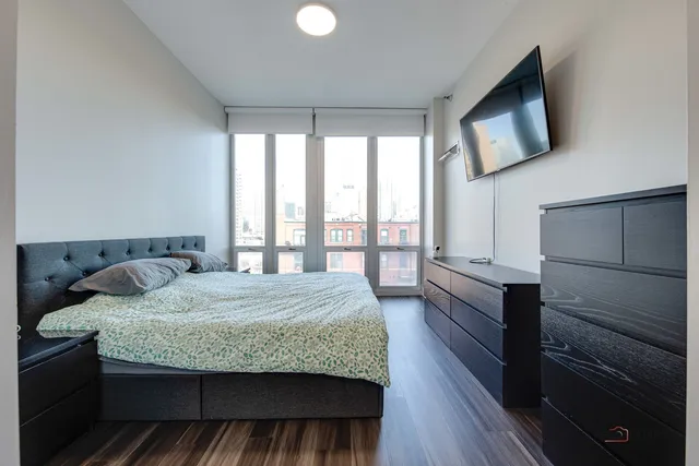 a bedroom with a large bed and a flat tv screen on dresser