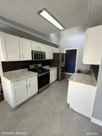 a kitchen with kitchen island granite countertop a stove top oven a sink dishwasher and a refrigerator with wooden floor