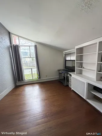 a view of an empty room with a window and wooden floor