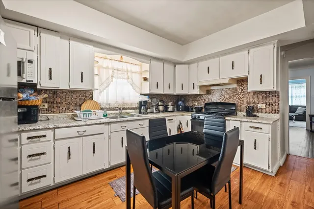 a kitchen with granite countertop white cabinets sink and stainless steel appliances
