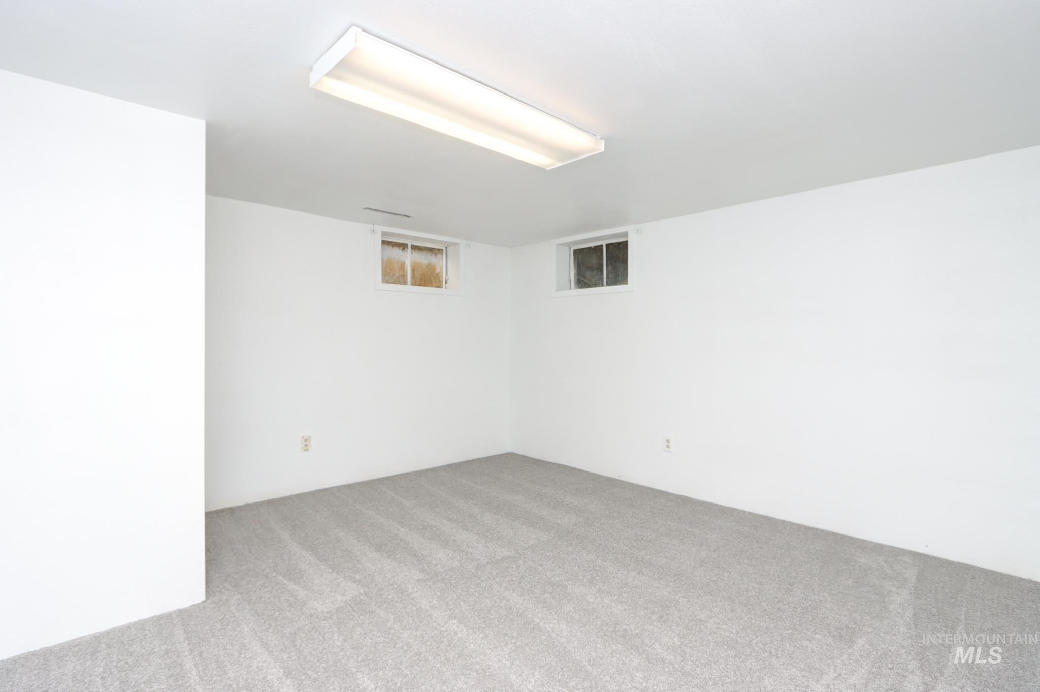 801 Thompson Avenue Nyssa, OR 97913 - Photo 26 of 46 Finished room with light gray patterned carpeting, white painted walls, and two recessed windows