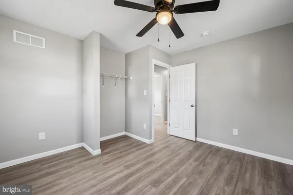 an empty room with wooden floor ceiling fan and windows