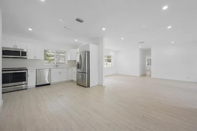 a view of a kitchen with a sink stove cabinets and empty room