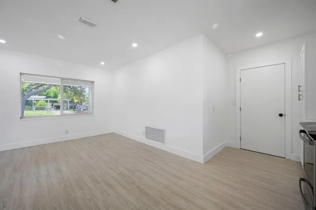 an empty room with wooden floor and window