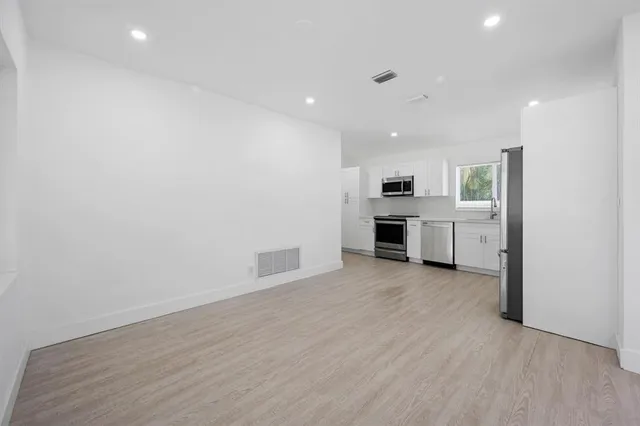an empty room with kitchen and fireplace