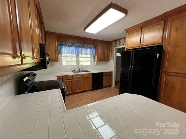 a kitchen with stainless steel appliances kitchen island granite countertop a refrigerator and a sink