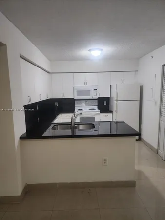 a kitchen with granite countertop white cabinets and refrigerator