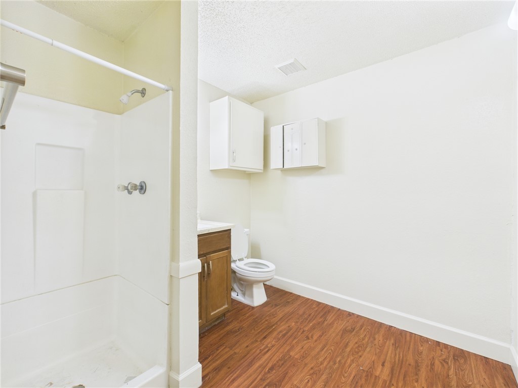 2702 Cavitt Avenue Bryan, TX 77801 - Photo 14 of 21 Full bath featuring vanity, a shower stall, dark wood-style flooring, and a textured ceiling