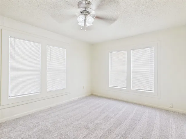 an empty room with a chandelier fan and windows